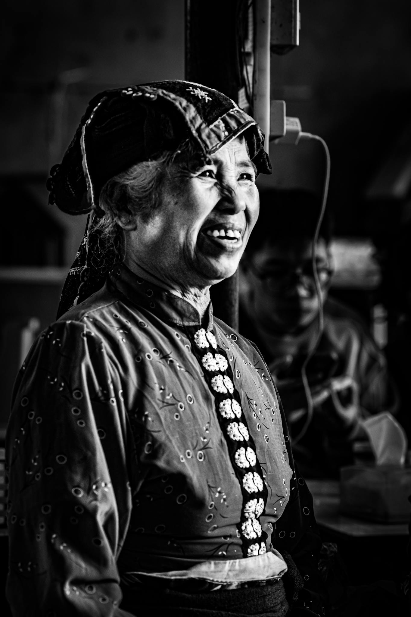 Captivating portrait of an elderly woman wearing traditional Hmong attire, smiling warmly.